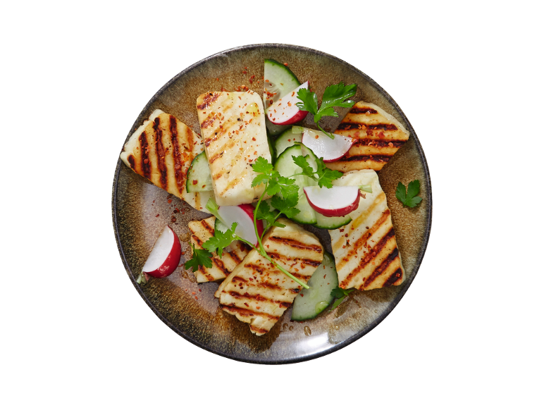 Žar halloumi s kumarami, redkvicami in peteršiljem na krožniku.