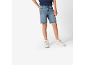 Deček v modrih jeans kratkih hlačah in belih supergah.