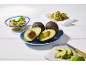 Sveži avokadi, guacamole in avokadovi toast na beli leseni mizi.