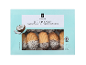 Škatla kokosovih petit four piškotov z mareličnim nadevom, delno pomočeni v čokolado in posuti s kokosovimi kosmiči.
