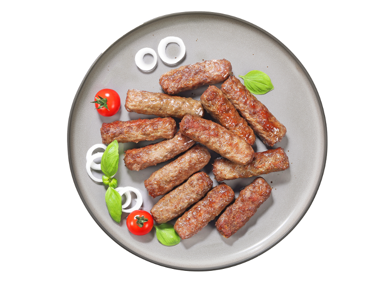 Žar mesni zvitki, čebulni obročki, paradižnik in bazilika na krožniku.