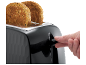 Črn opekač kruha z dvema rezinama polnozrnatega toasta, prst pritiska ročico.
