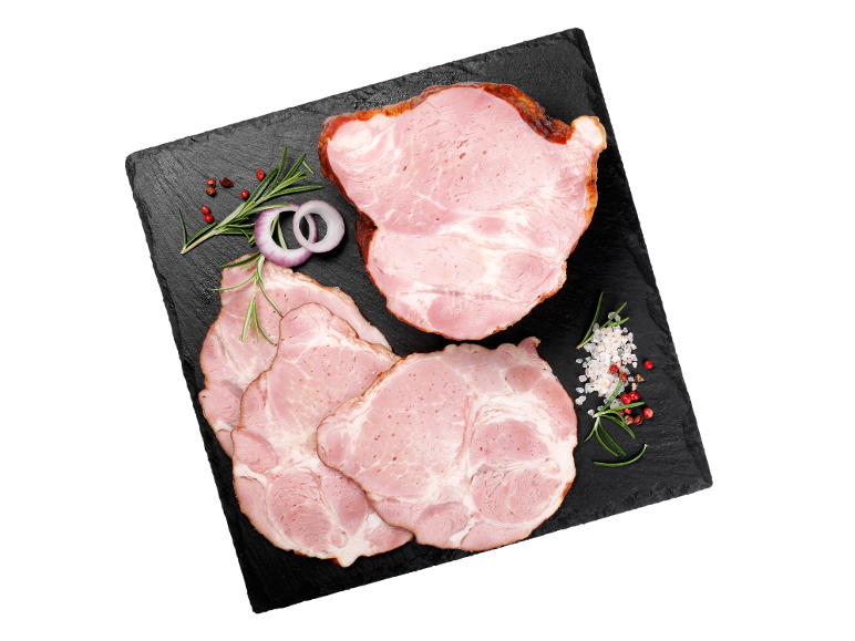 Narezana dimljena šunka z rožmarinom, čebulo in poprom na črni skrilavčevi plošči.