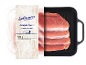 Sveži svinjski zrezki v pakiranju, 500 g, s črno žar ponevjo ob strani.