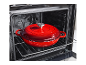 Rdeč litoželezni lonec v pečici na rešetki.