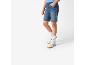 Deček v modrih jeans kratkih hlačah, modri majici in belih supergah z modrimi detajli.