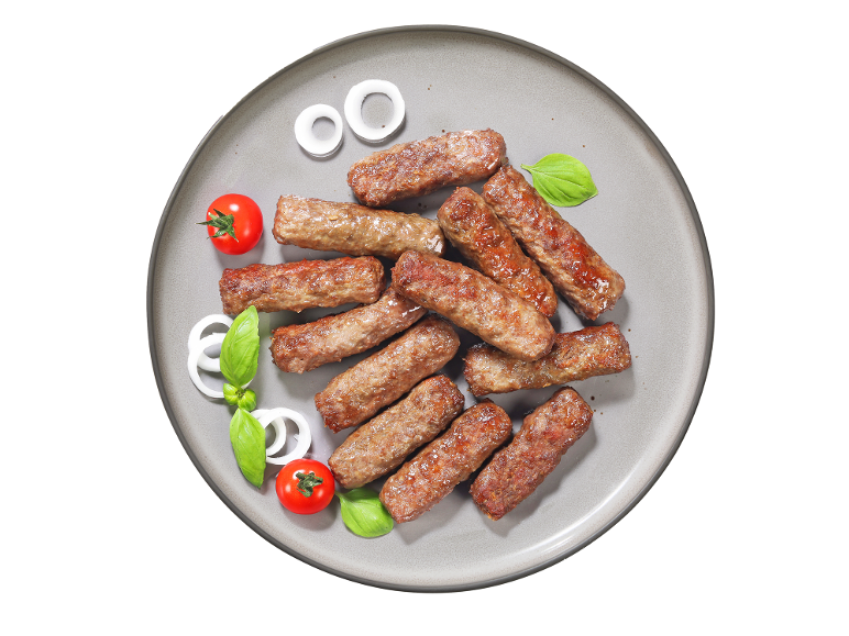 Žar mesni zvitki, čebulni obročki, paradižnik in bazilika na krožniku.