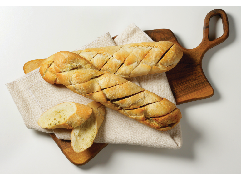 Narezan česnov kruh na leseni deski za rezanje s kuhinjsko krpo