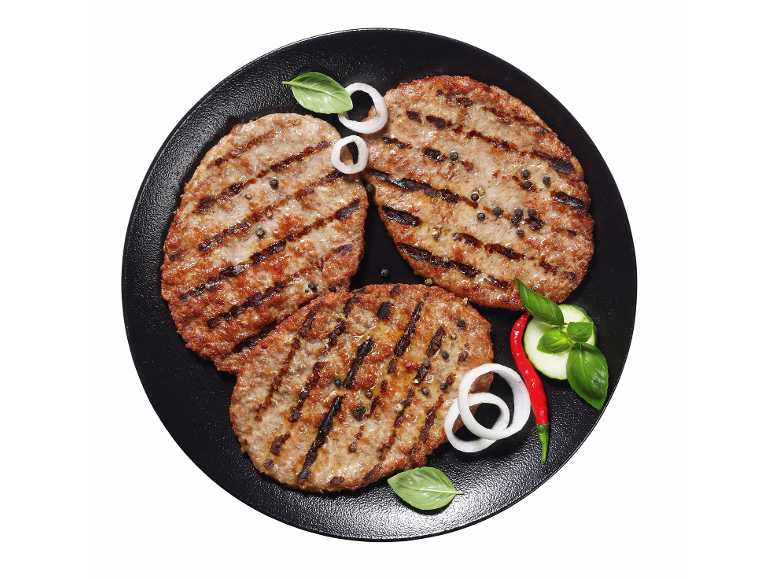 Žar burgerji s poprom, čebulo, baziliko, kumarami in čilijem na črnem krožniku.