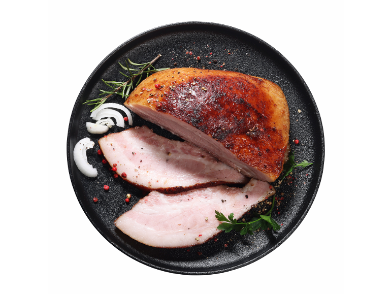 Pečena svinjska trebušna slanina z zelišči in začimbami na črnem krožniku.