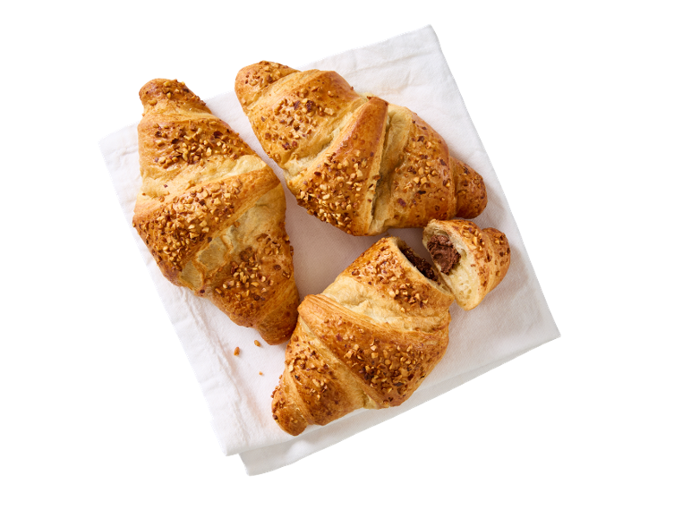Trije rogljički z oreščki na beli brisači, eden s čokoladnim polnilom.