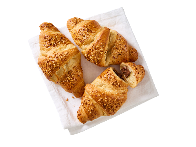 Trije rogljički z oreščki na beli brisači, eden s čokoladnim polnilom.