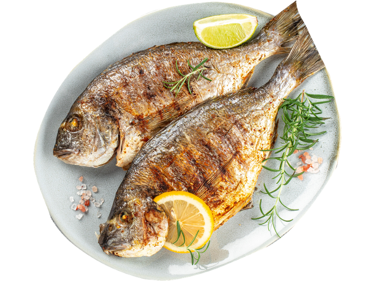 Dve pečeni oradi z limono, limeto in rožmarinom na krožniku.