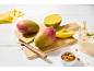 Sveži mangi, narezan mango in mangov smuti z mandlji na leseni mizi.