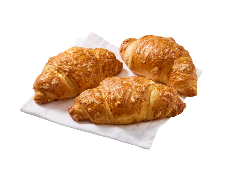 Trije zlato rjavi rogljički s sirom na beli papirnati brisači.