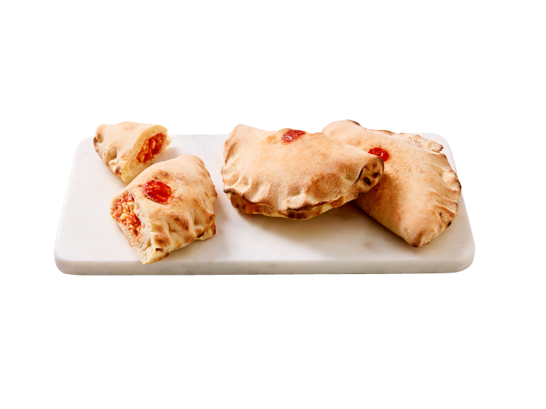 Sveže pečene polnjene kalcone na beli marmorni deski.
