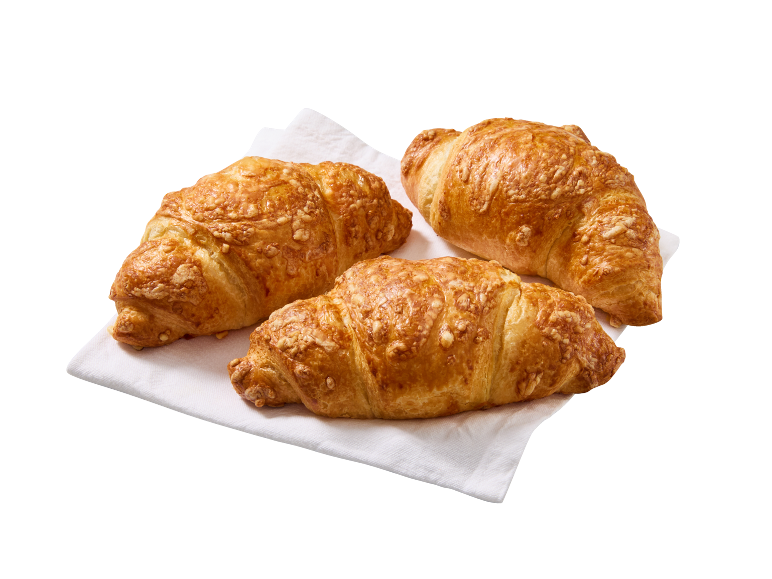 Trije zlato rjavi rogljički s sirom na beli papirnati brisači.