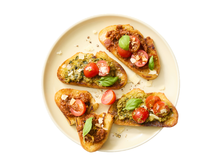 Bruschetta s pestom in paradižnikom ter bruschetta s paradižnikovo pašteto in paradižnikom.