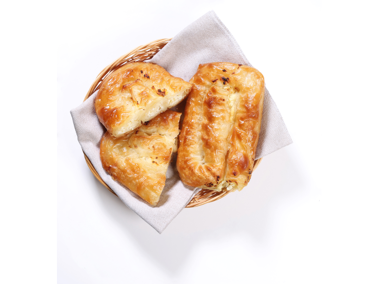 Zlato rjav sirov burek v pleteni košari z laneno krpo.