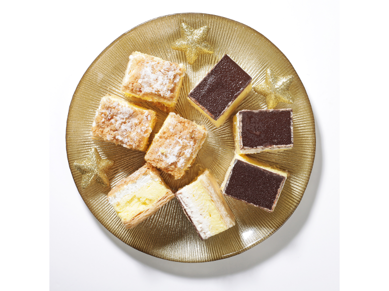 Kremne in čokoladne torte na zlatem krožniku z okrasnimi zvezdami.