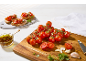 Sveža bruschetta s paradižnikom, zelišči in olivnim oljem na beli leseni mizi.