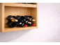 Lesena stenska polica s črnim stojalom za vino, ki vsebuje steklenice vina.