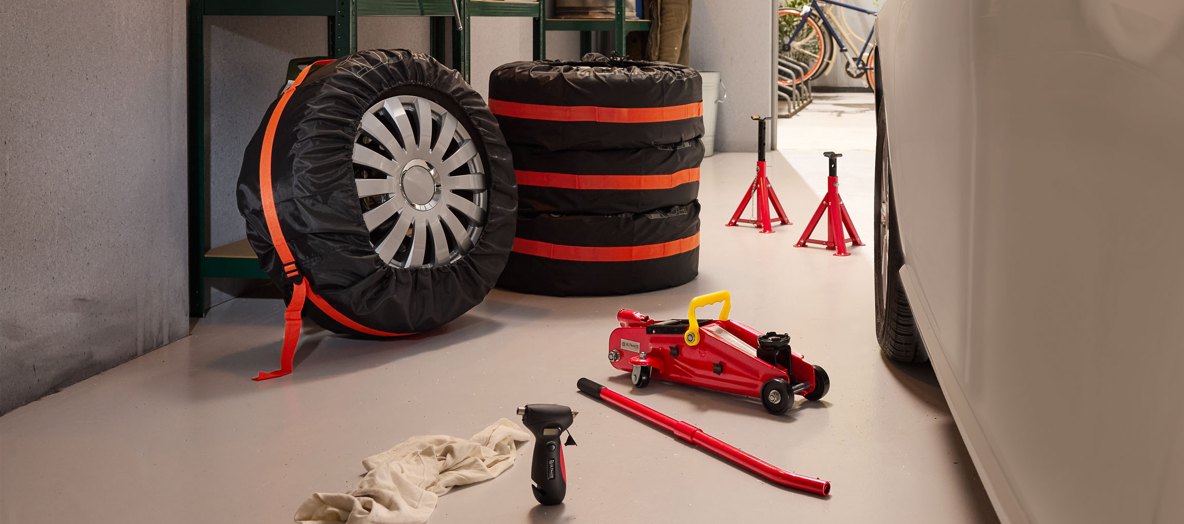 Avtomobilske pnevmatike s prevlekami, dvigalka in stojala v garaži.