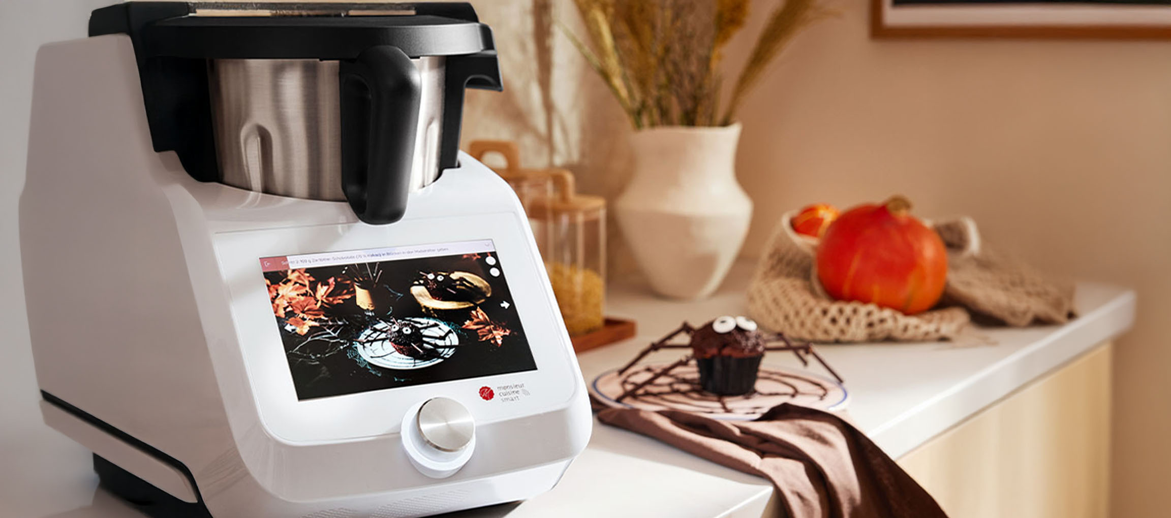 Kuhinjski robot z zaslonom na dotik prikazuje recept za noč čarovnic, poleg pajkovega mafina.
