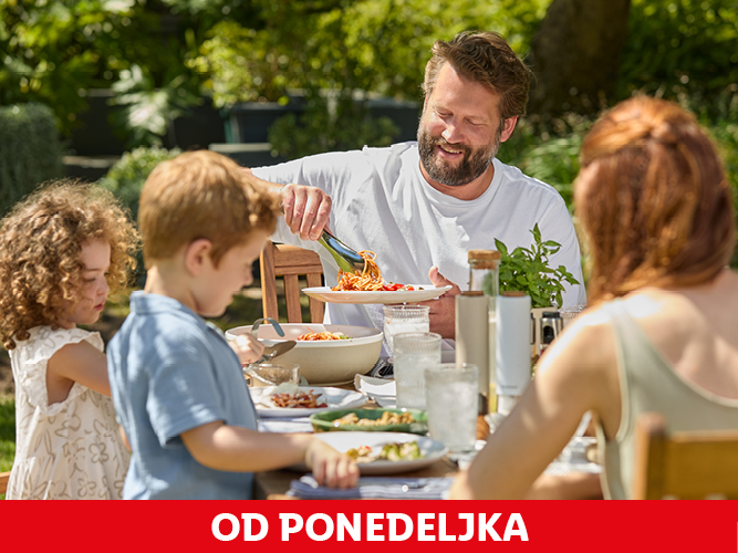 Družina uživa ob kosilu na prostem.