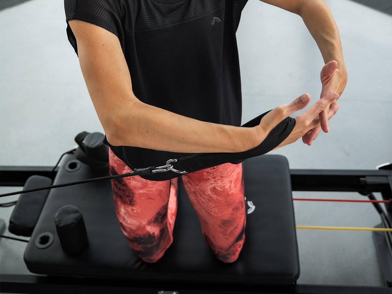 Ženska telovadi z uporovnimi trakovi na napravi za pilates.