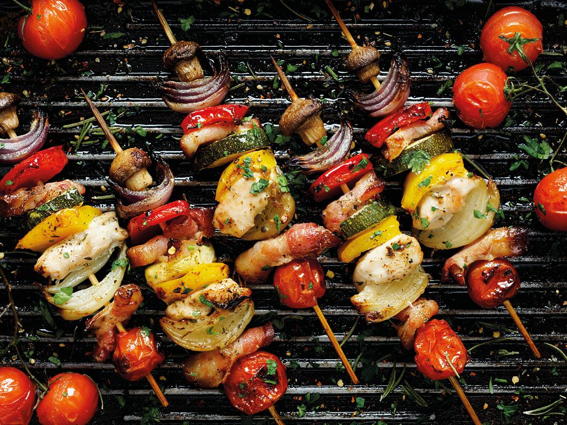 Piščančji in zelenjavni ražnjiči na žaru, vključno s paradižnikom, gobami in čebulo.