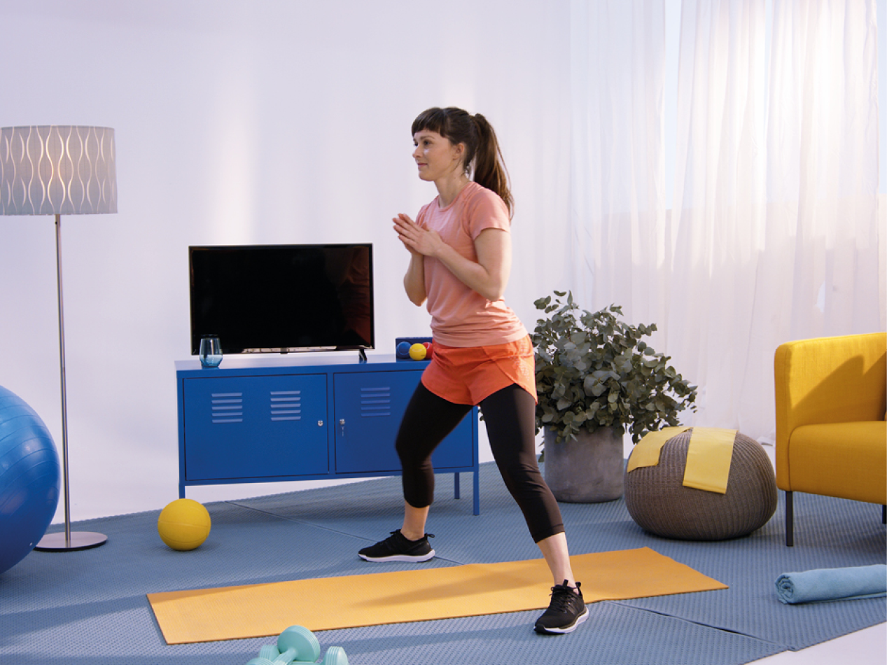 Ženska telovadi v dnevni sobi z opremo za fitnes in pohištvom.