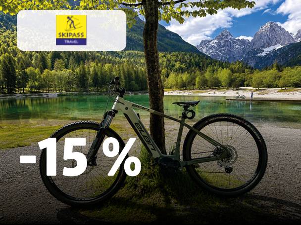 Gorsko kolo ob jezeru z gorami v ozadju, popust -15% in logotip smučarske vozovnice.