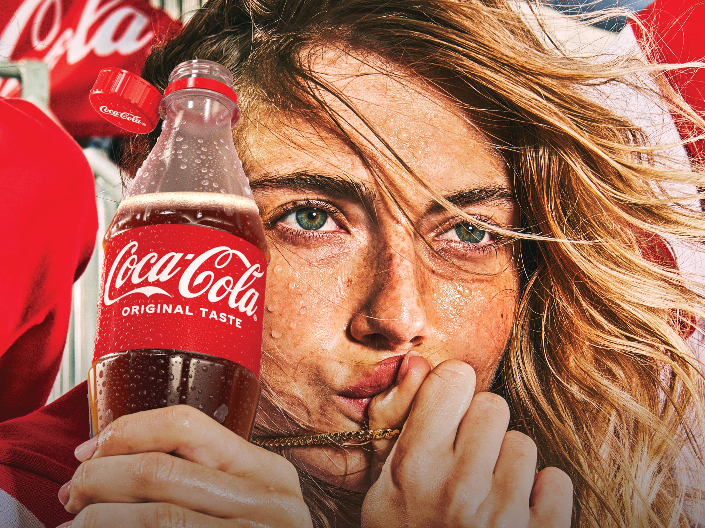 Oseba s potnimi kapljicami na obrazu drži ohlajeno pijačo v steklenici.