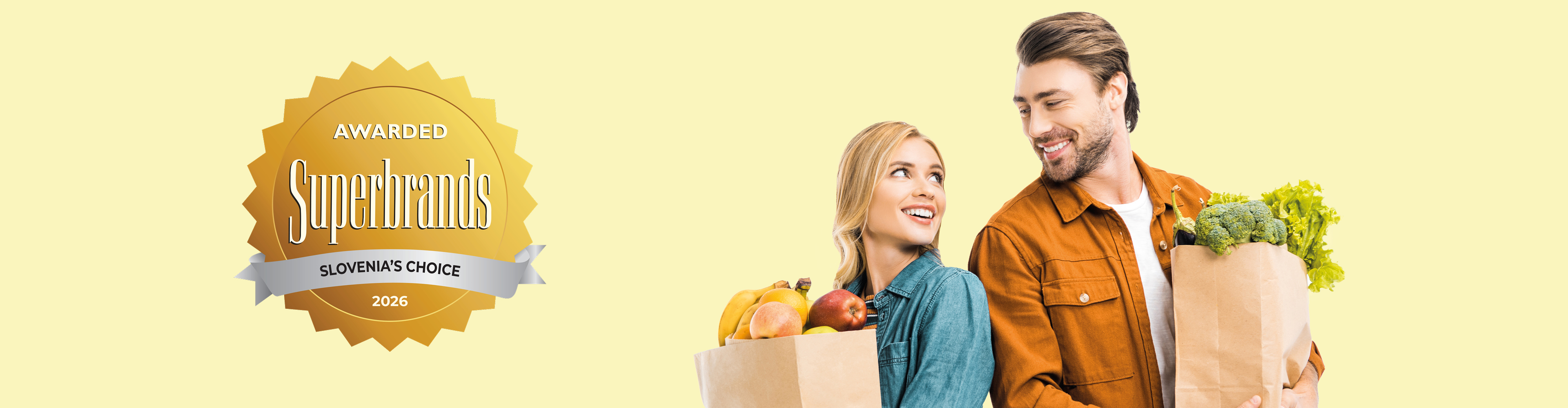 Nasmejan par drži papirnate vrečke s sadjem in zelenjavo, ob strani je zlata nagrada.