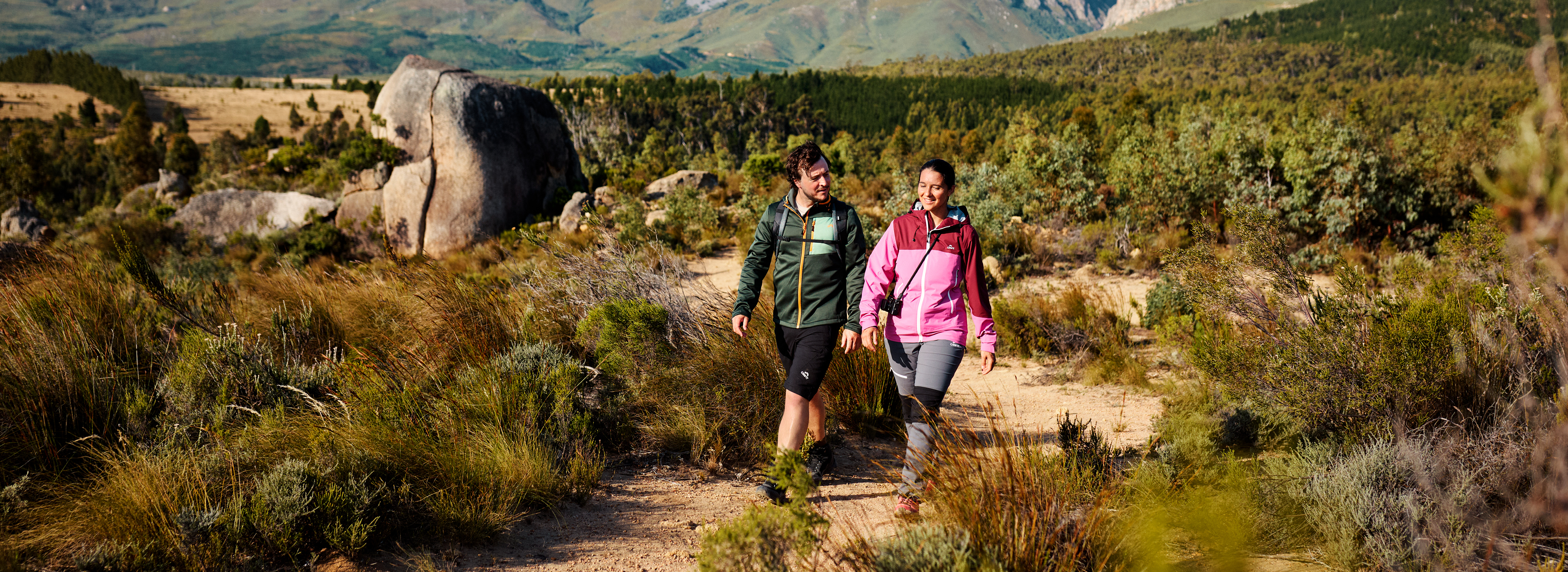 Par v pohodniških oblačilih in obutvi hodi po gorski poti.