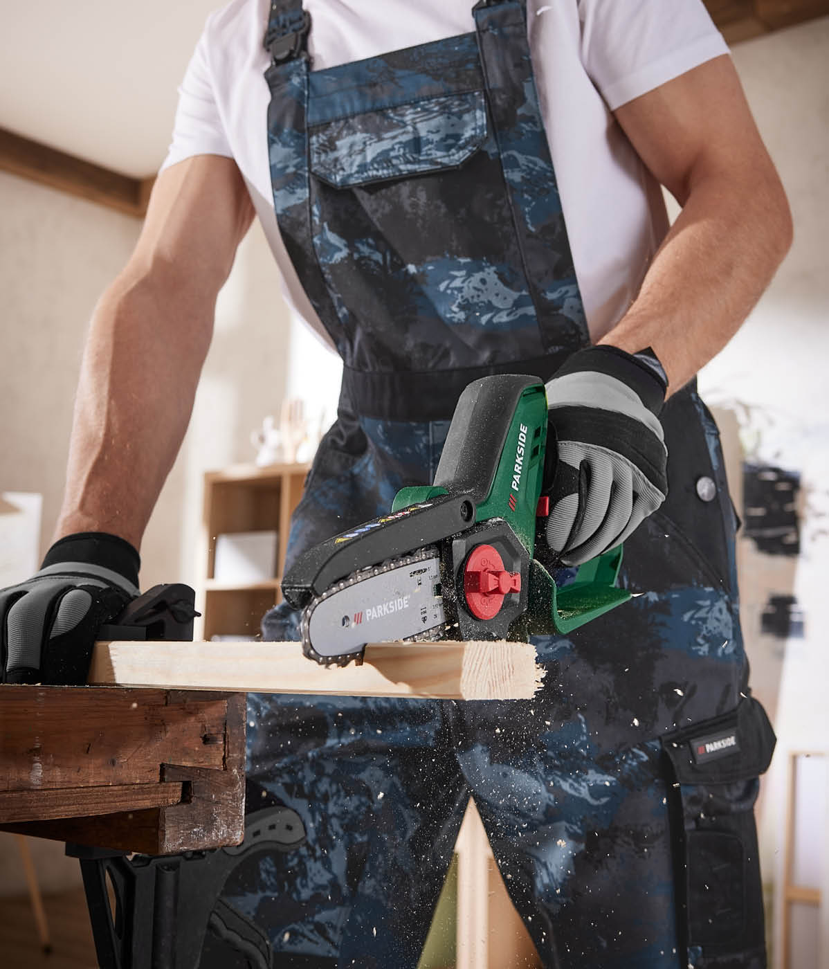 Delavec uporablja akumulatorsko verižno žago Parkside za rezanje lesa.