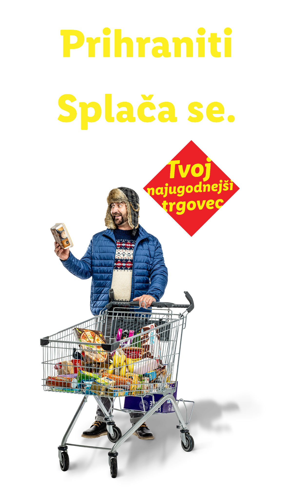 Moški v zimski kapi in jakni s polnim nakupovalnim vozičkom, z napisom »Prihraniti v vsakem letnem času? Splača se.«