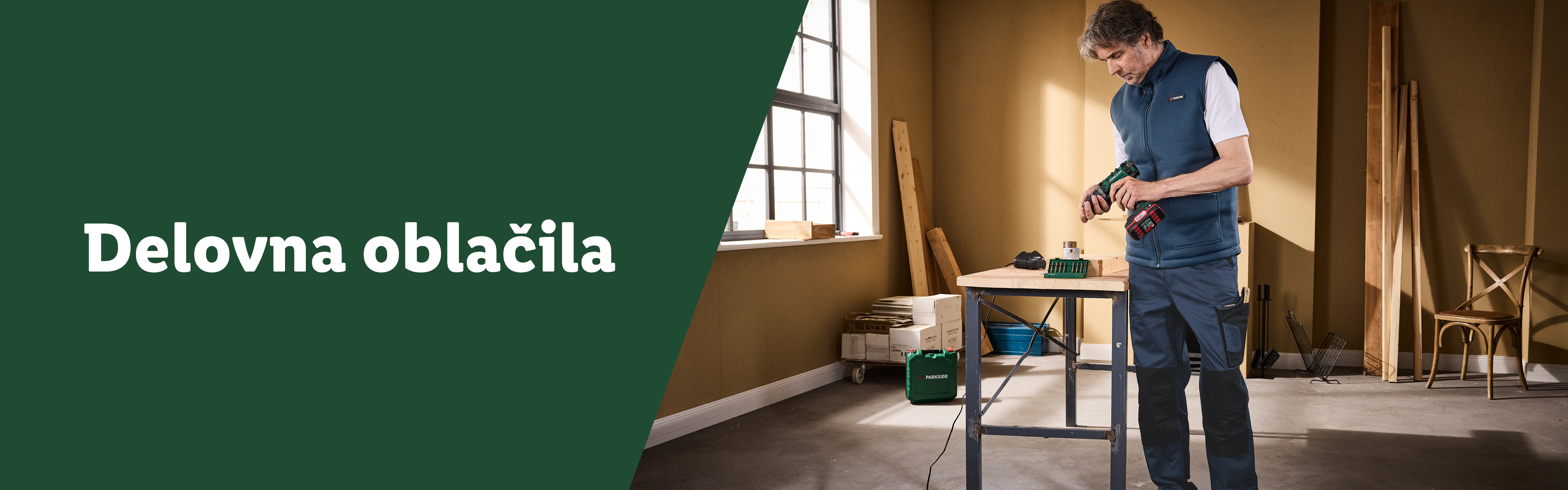 Moški v delovnih oblačilih Parkside z akumulatorskim vrtalnikom in delovno mizo.