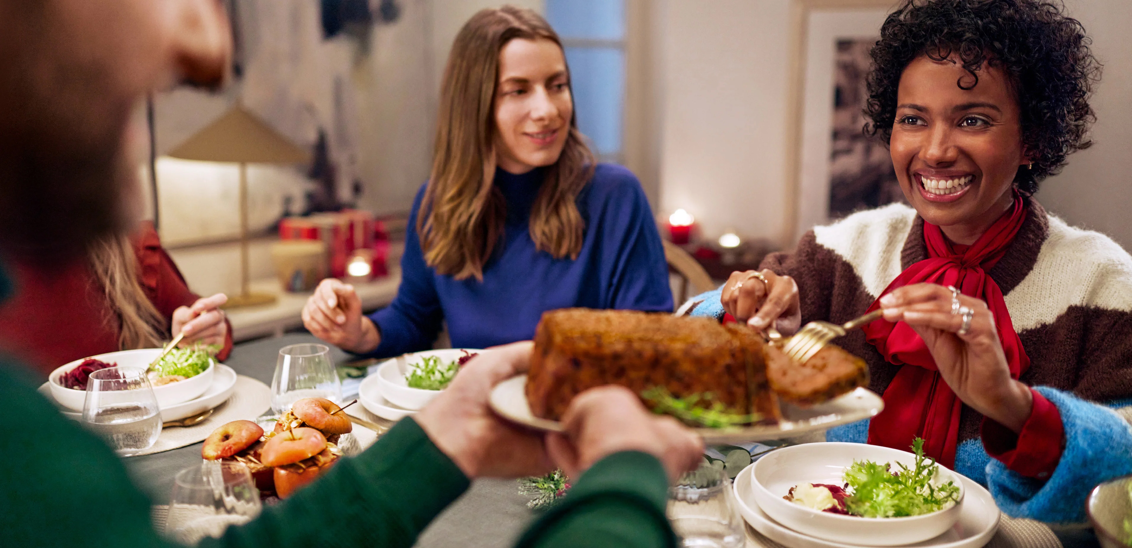 Prijatelji uživajo v praznični večerji z mesno štruco in solato.
