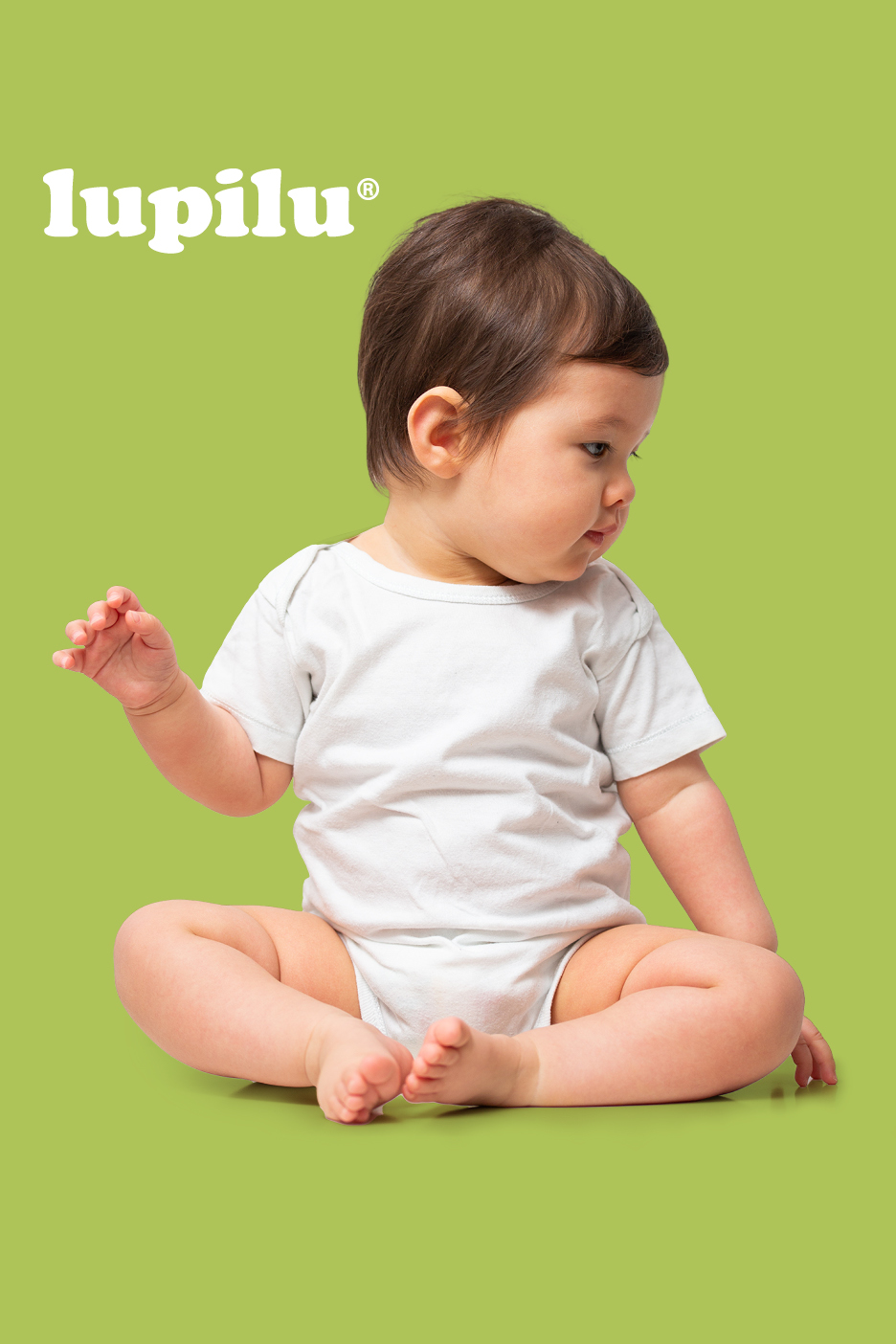 Dojenček v belem bodiju sedi na zelenem ozadju, zgoraj levo je napis »lupilu®«.