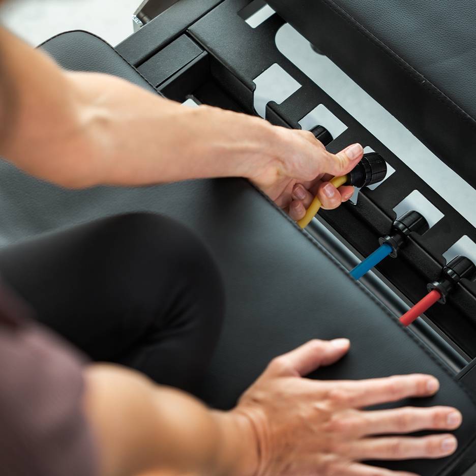 Oseba prilagaja vadbene trakove na vadbeni klopi.