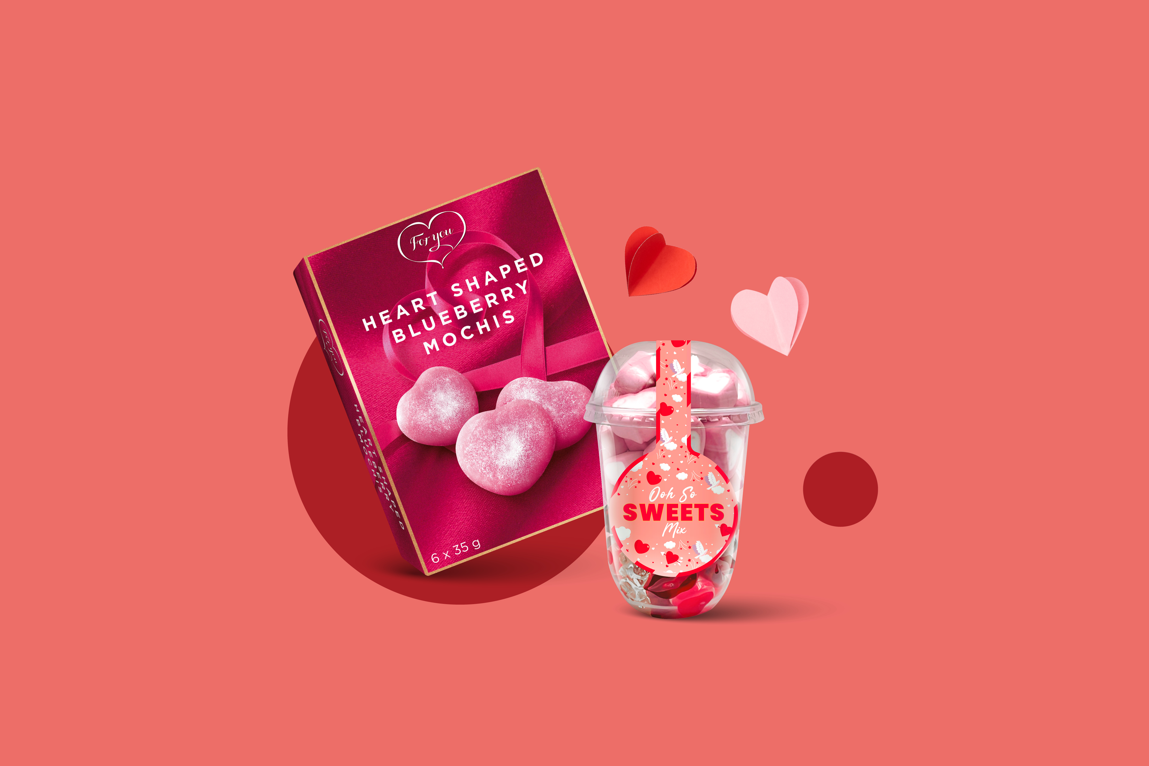 Škatla srčastih močijev z borovnicami in skodelica sladkarij na rdečem ozadju.