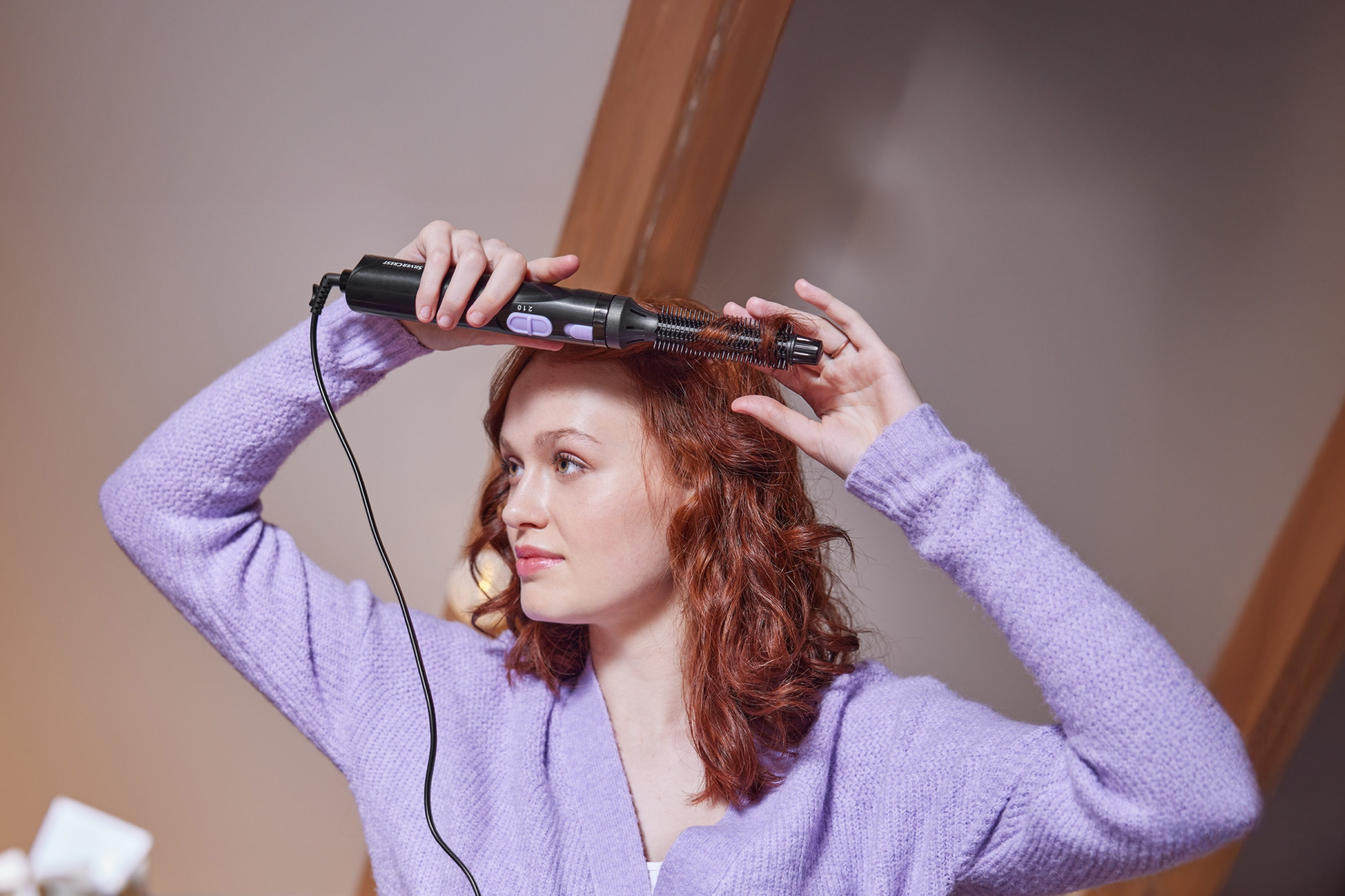 Ženska si s krtačo za oblikovanje las Silvercrest oblikuje rdeče lase.