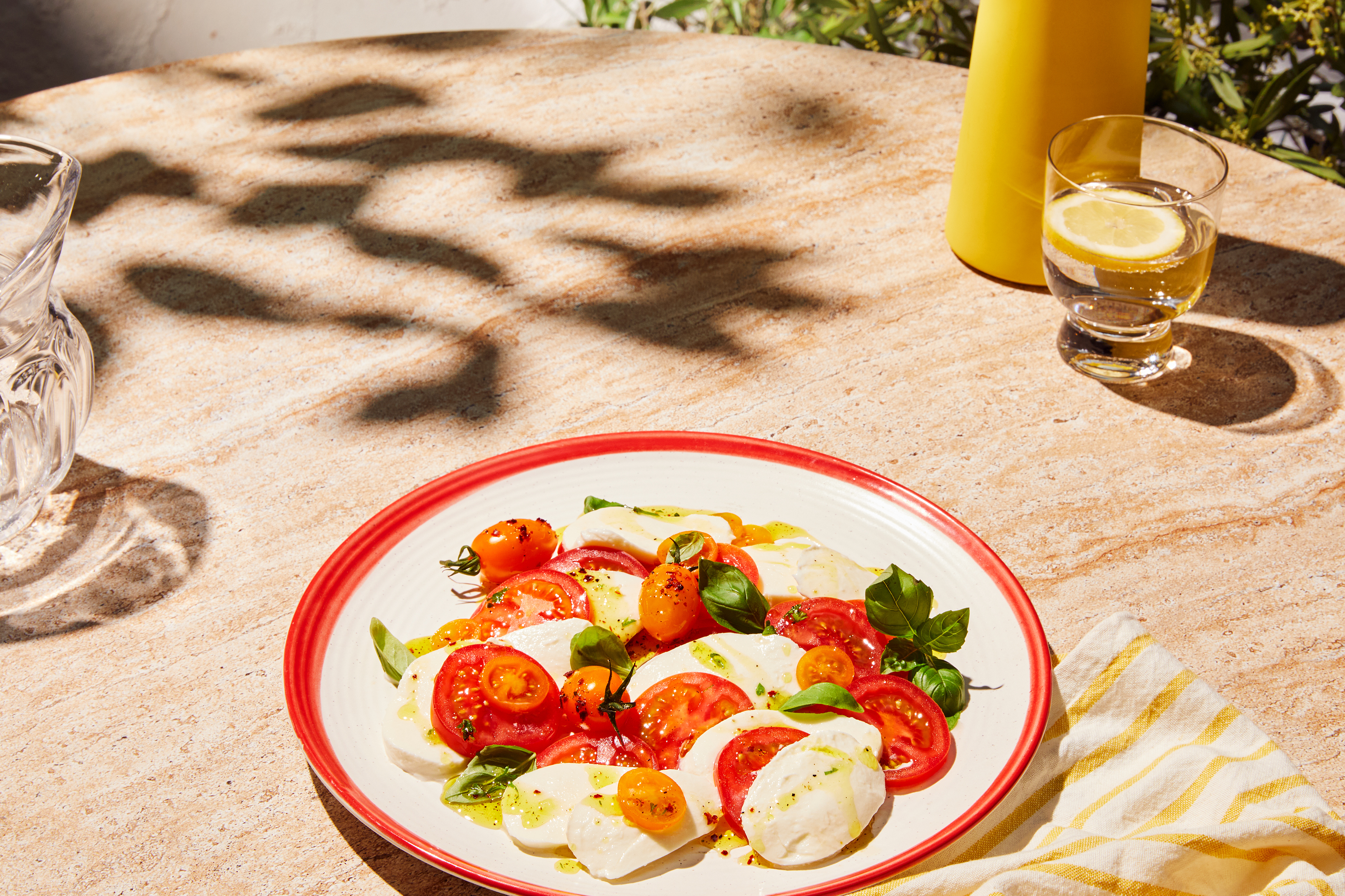 Caprese solata s paradižnikom, mocarelo in baziliko na kamniti mizi.