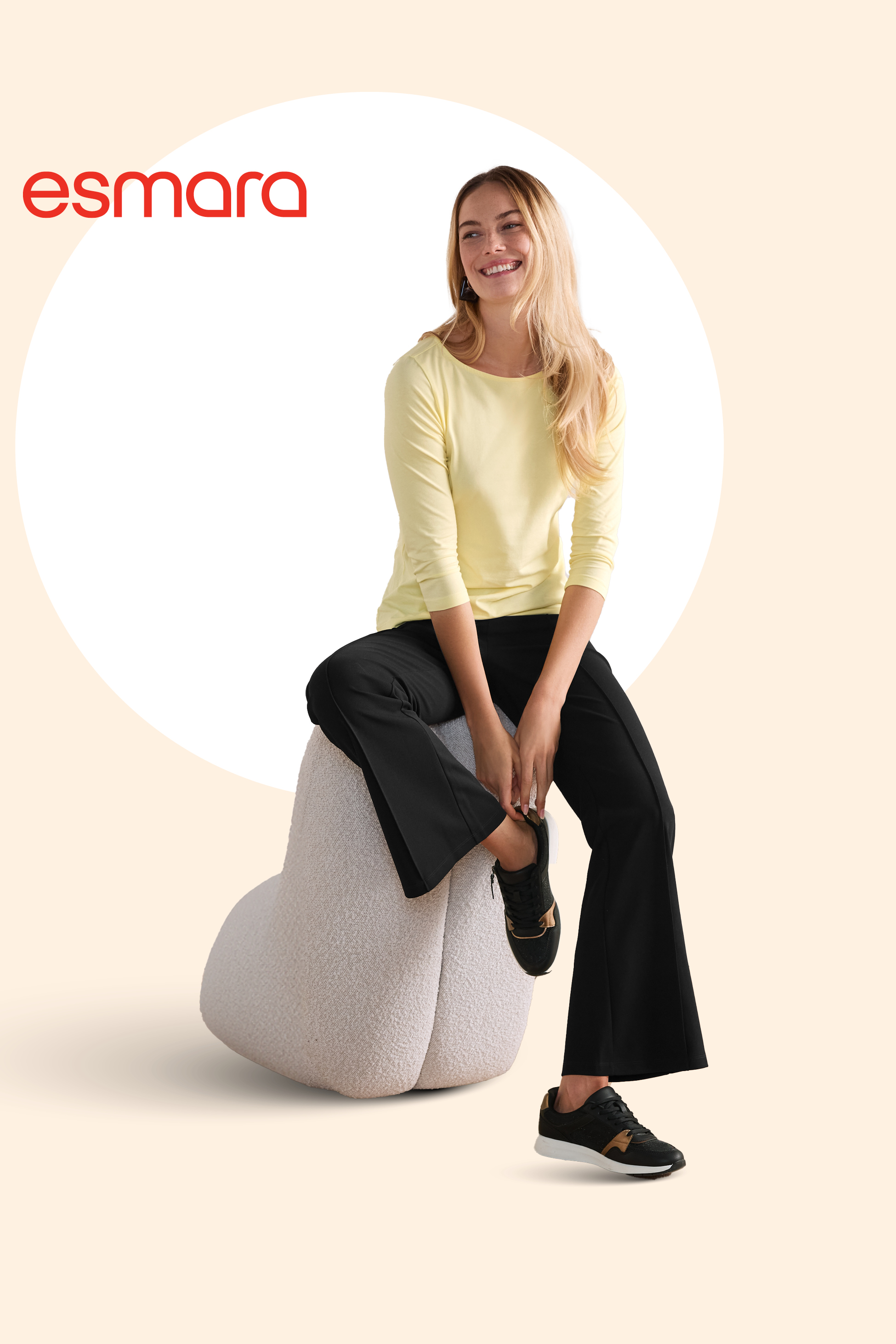 Ženska v rumeni majici z dolgimi rokavi in črnih hlačah, sedi na belem tabureju.