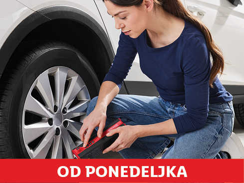 Ženska uporablja prenosni kompresor za avtomobilska kolesa.