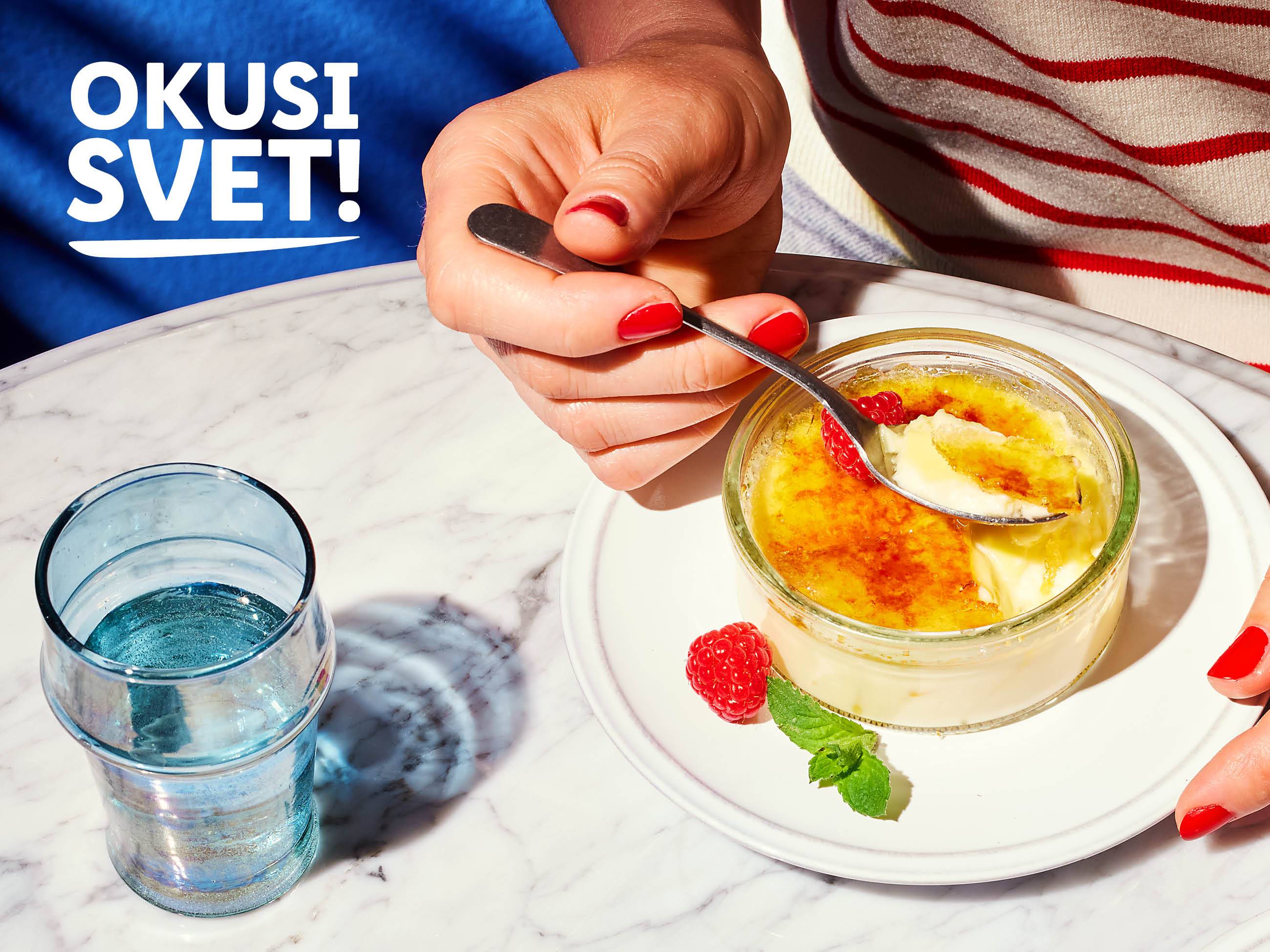 Ženska uživa v kremni sladici crème brûlée z malinami.