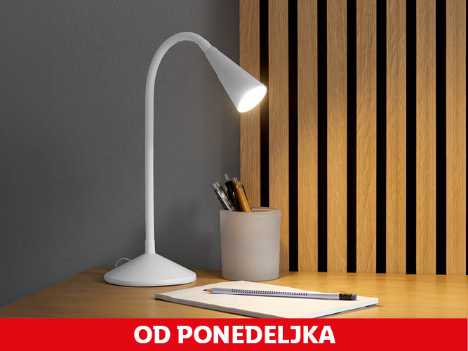 Elegantna bela namizna svetilka osvetljuje delovno mizo s pisalom in beležnico.
