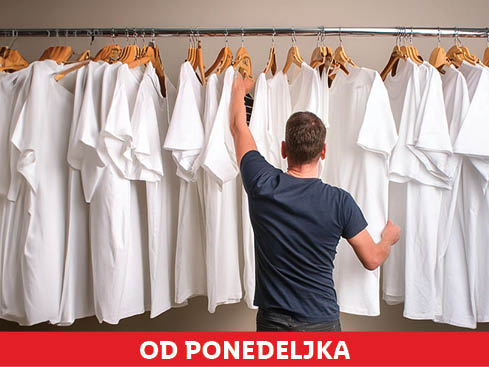 Moški izbira bele majice iz omare.